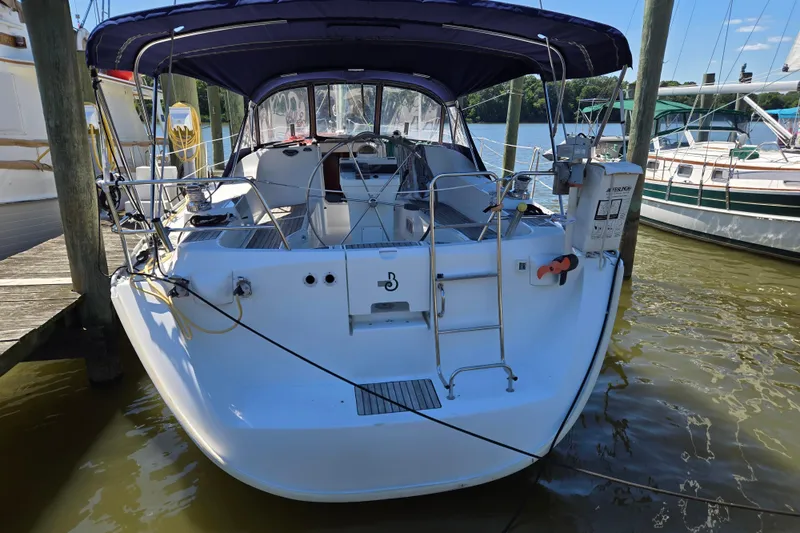 Slide: The Image of 2003 Beneteau 393 sailboat docked, featuring a spacious cockpit and blue canopy. - 50