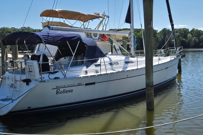 Slide: The Image of 2003 Beneteau 393 sailboat docked in calm waters, featuring a sleek design and blue canopy. - 53