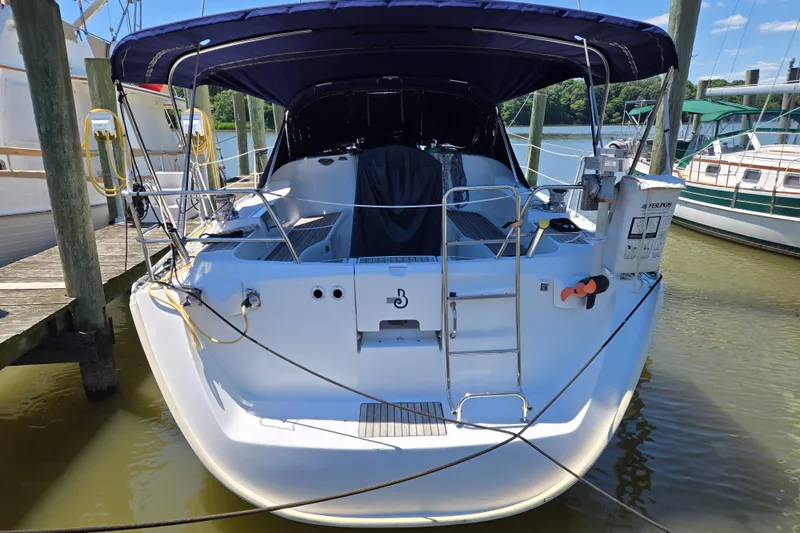 Slide: The Image of 2003 Beneteau 393 sailboat docked, featuring a spacious cockpit and protective canopy. - 6