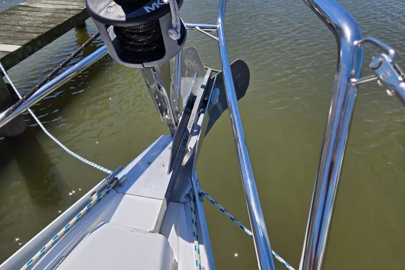 Slide: The Image of Bow of 2003 Beneteau 393 sailboat with anchor and railing, docked on calm water. - 7