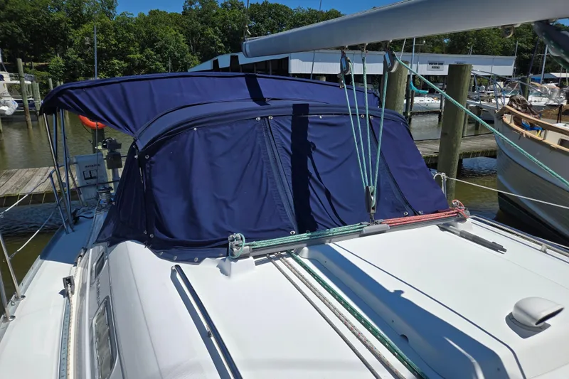 Slide: The Image of 2003 Beneteau 393 sailboat with blue canvas cover docked at marina. - 9