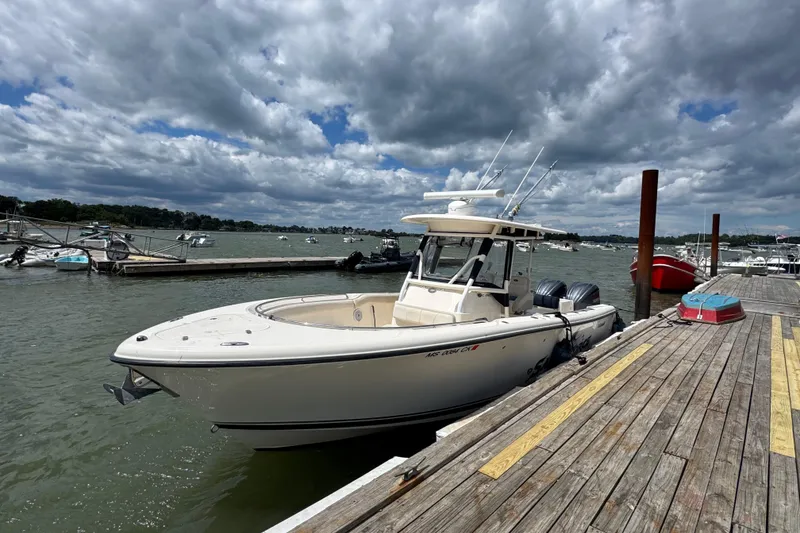 Slide: The Image of 2011 Pursuit C 280 Center Console boat docked on a sunny day with cloudy skies. - 2