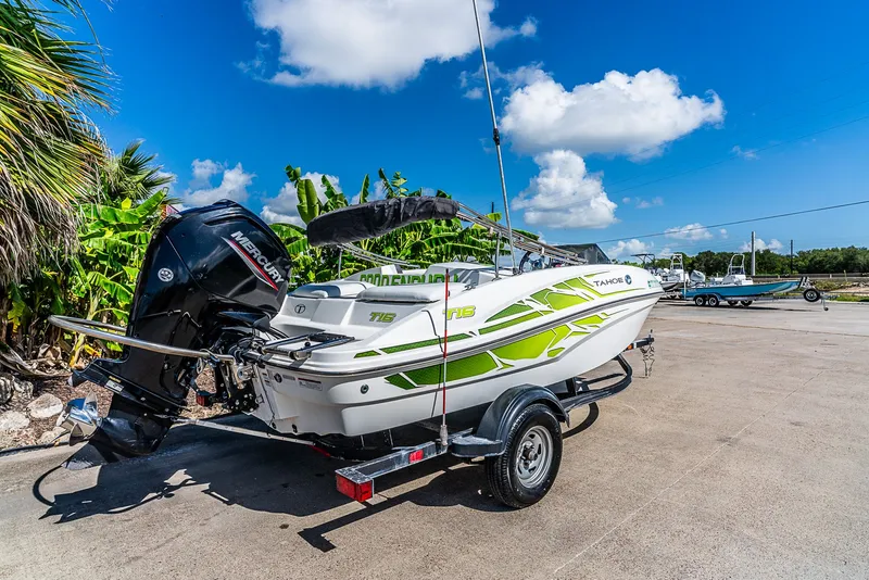 Slide: The Image of A white 2021 Tracker Tahoe boat on a trailer, surrounded by palm trees. - 3