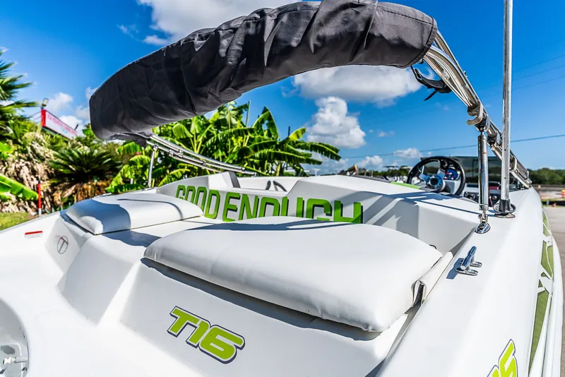 Slide: The Image of A 2021 Tracker Tahoe boat with white upholstery and green lettering, surrounded by palm trees. - 5
