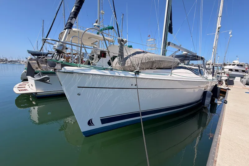 Slide: The Image of 2008 Hunter 45 Deck Salon sailboat docked in a marina under clear blue skies. - 2