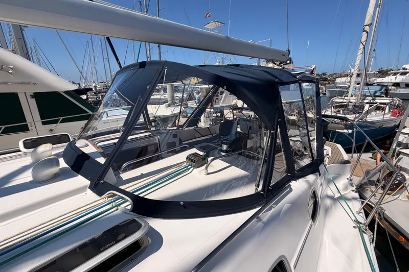 Slide: The Image of 2008 Hunter 45 Deck Salon sailboat docked in marina, featuring sleek design and protective canopy. - 37