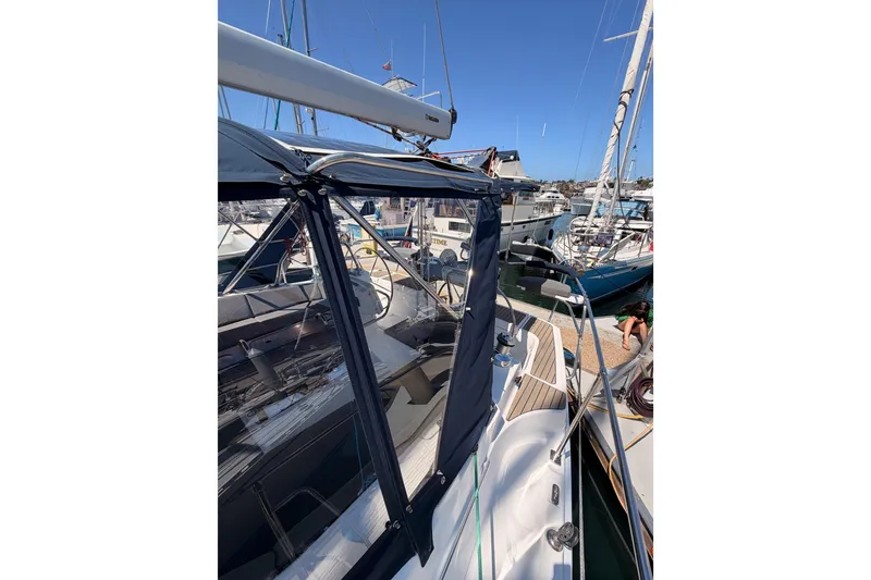 Slide: The Image of 2008 Hunter 45 Deck Salon sailboat docked at marina, featuring sleek design and blue canopy. - 38