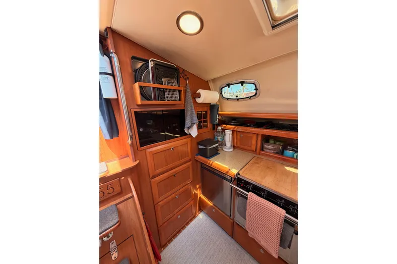 Slide: The Image of Interior of 2008 Hunter 45 Deck Salon yacht kitchen with wooden cabinetry and appliances. - 52