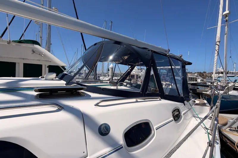 Slide: The Image of 2008 Hunter 45 Deck Salon sailboat docked in marina, featuring sleek design and blue canopy. - 7