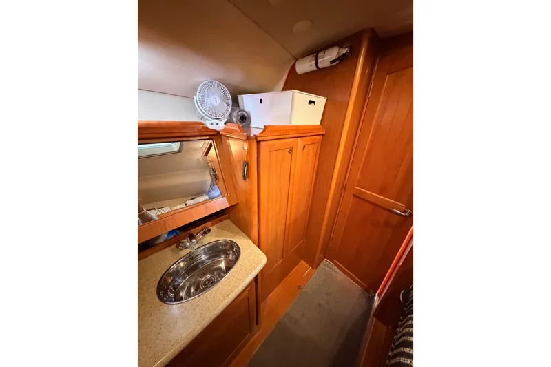 Slide: The Image of Interior of 2008 Hunter 45 Deck Salon, featuring wooden cabinetry and a compact sink area. - 77