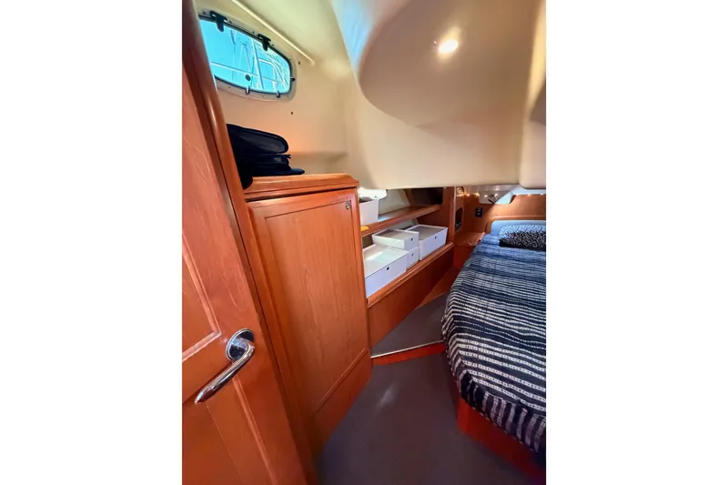 Slide: The Image of Interior cabin of 2008 Hunter 45 Deck Salon with wood cabinetry and striped bedding. - 90