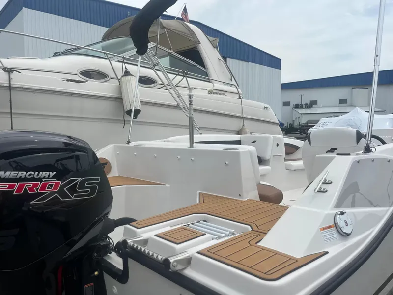 Slide: The Image of A 2027 Starcraft SVX 171 OB with a Mercury Pro XS engine, docked beside a larger yacht. - 3