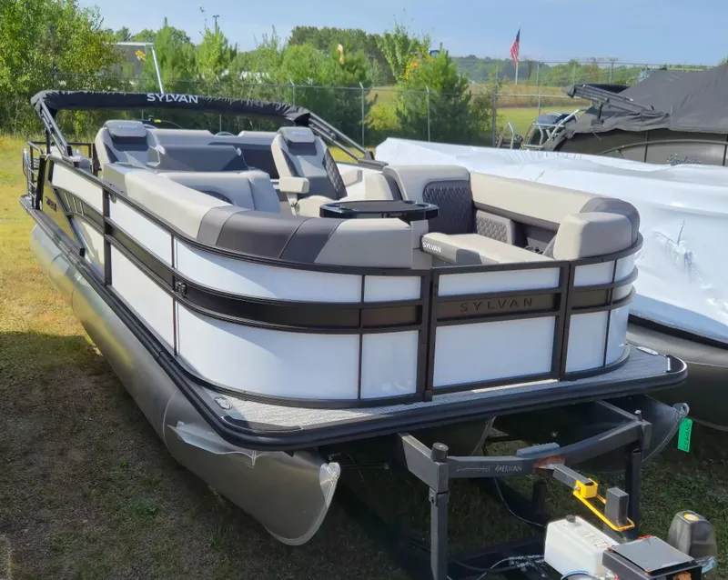The Image of A 2027 Sylvan L-3 ULZ/TT pontoon boat is on a trailer outdoors. - 1