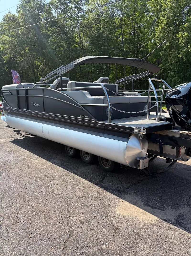 Slide: The Image of A 2027 Barletta CABRIO C22UC/TT pontoon boat on a trailer, surrounded by trees. - 18