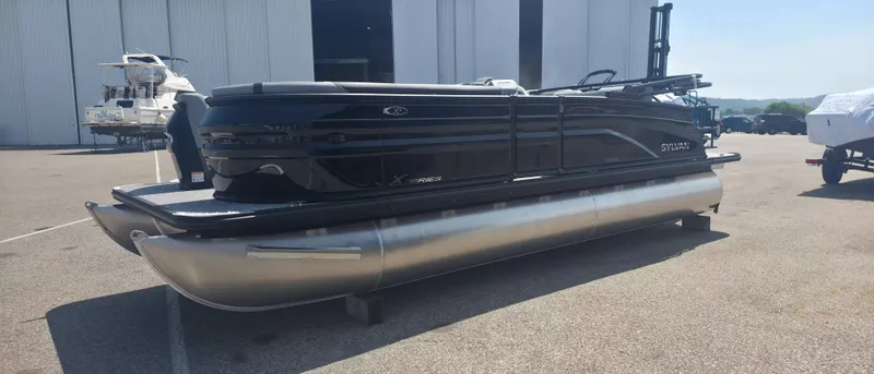 Slide: The Image of A 2026 Sylvan X3 ULZ FG/TT pontoon boat is parked on a lot in front of a building. - 2