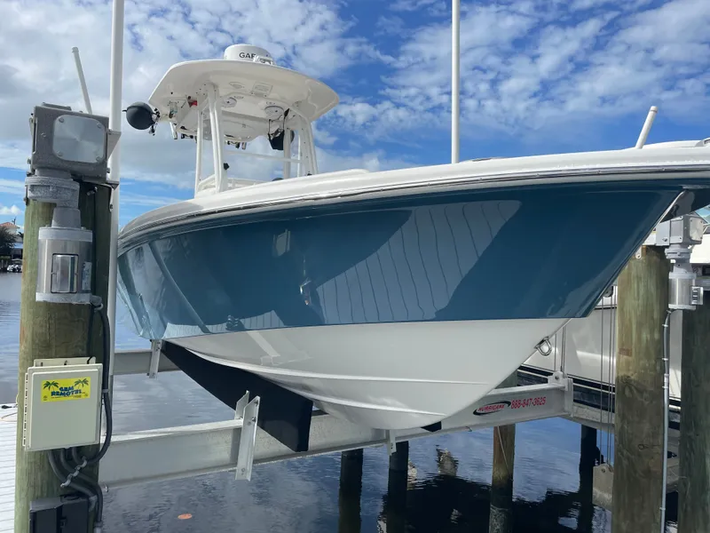 The Image of A 2012 Everglades 243 Center Console boat is seen on a boat lift above the water. - 0