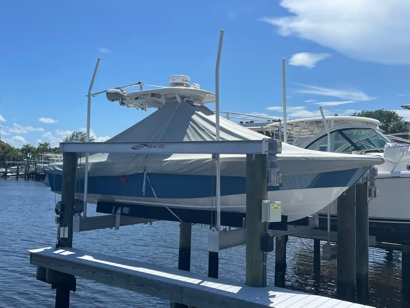 Slide: The Image of A 2012 Everglades 243 Center Console boat is on a lift above the water, covered with a tarp. - 2