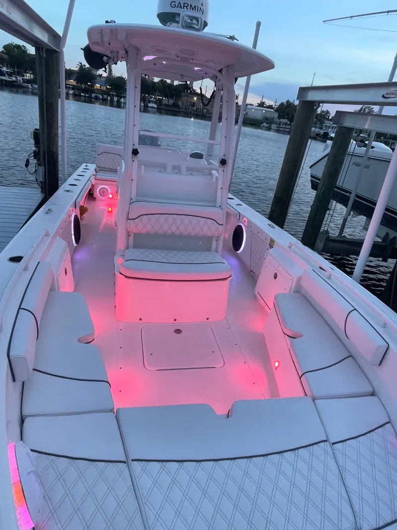 Slide: The Image of A 2012 Everglades 243 Center Console boat with pink lighting, docked at a marina. - 24