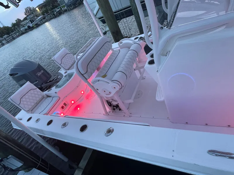 Slide: The Image of A 2012 Everglades 243 Center Console boat docked. It features red lights and cushioned seating. - 25