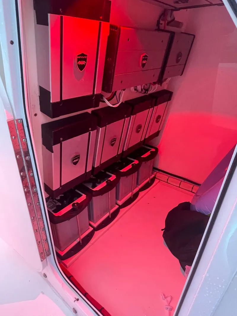 Slide: The Image of View of a boat engine room with multiple batteries and red lighting. - 26