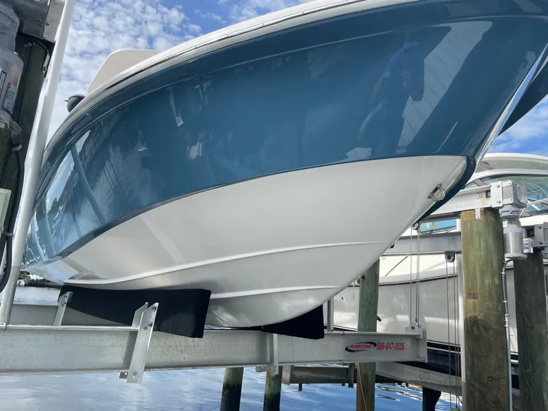 Slide: The Image of A 2012 Everglades 243 Center Console boat on a lift above the water. - 3