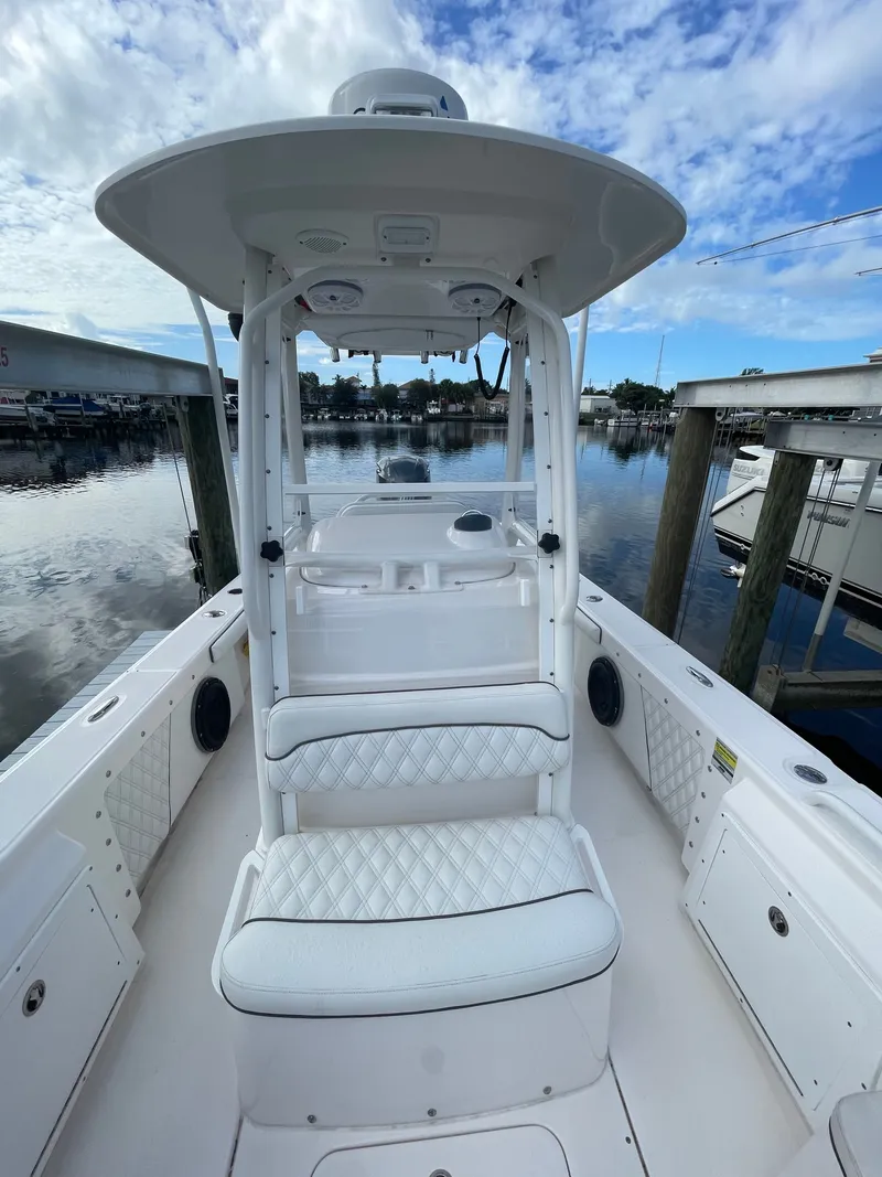 Slide: The Image of A 2012 Everglades 243 Center Console boat at the dock. It features white upholstery and a T-top. - 8