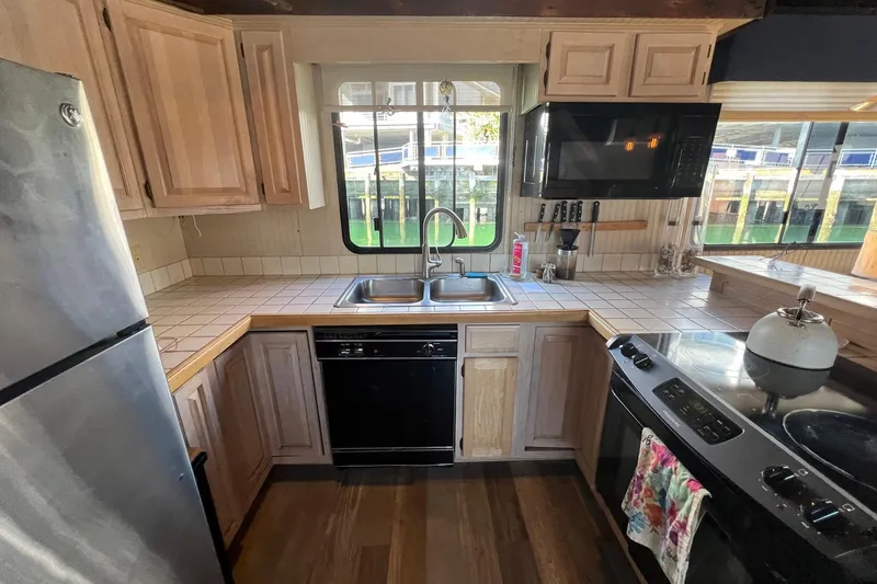 Slide: The Image of 1993 Sumerset houseboat kitchen with wooden cabinets, stainless steel appliances, and tiled countertops. - 11