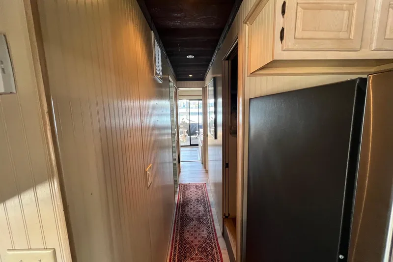 Slide: The Image of Narrow hallway inside a 1993 Sumerset houseboat with wooden cabinets and a patterned rug. - 14