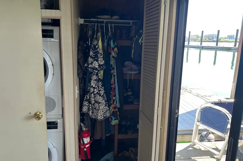 Slide: The Image of Interior of a 1993 Sumerset houseboat closet with clothes, washer, and fire extinguisher. - 26