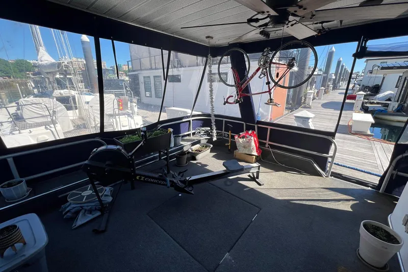 Slide: The Image of 1993 Sumerset houseboat interior with exercise equipment and bicycle, docked at a marina. - 3