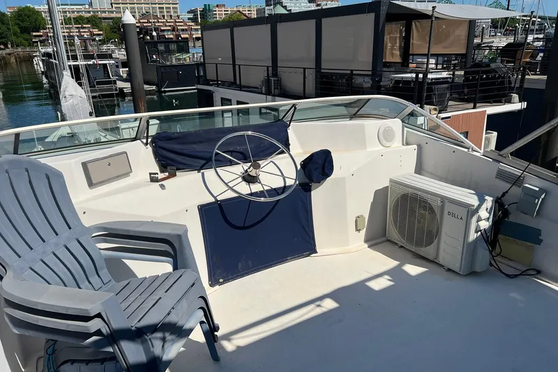Slide: The Image of 1993 Sumerset houseboat helm with steering wheel, chairs, and air conditioning unit at marina. - 35