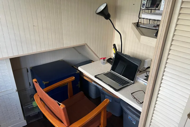 Slide: The Image of Compact workspace on a 1993 Sumerset houseboat with laptop, chair, and storage bins. - 38