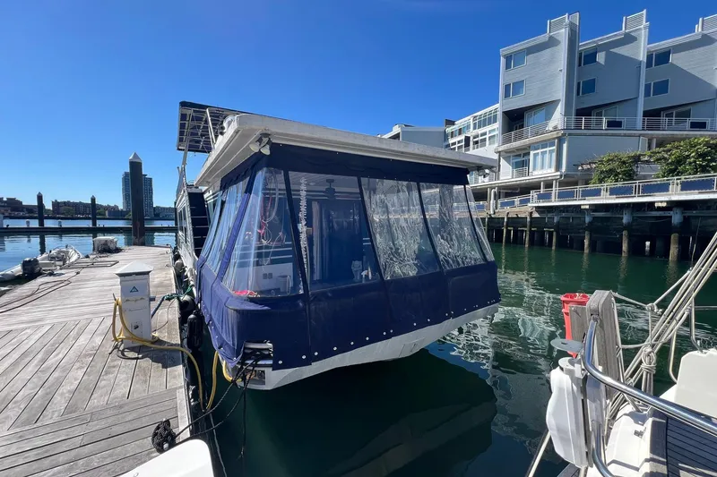 Slide: The Image of 1993 Sumerset houseboat docked at marina, featuring blue canopy and waterfront buildings. - 4
