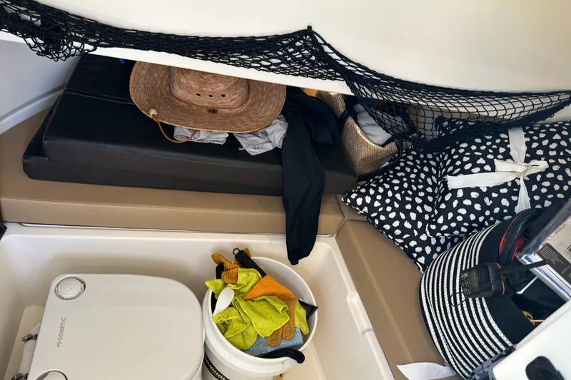 Slide: The Image of Interior storage of 2022 Sea Ray SLX 250 boat with hats, cushions, and cleaning supplies. - 31