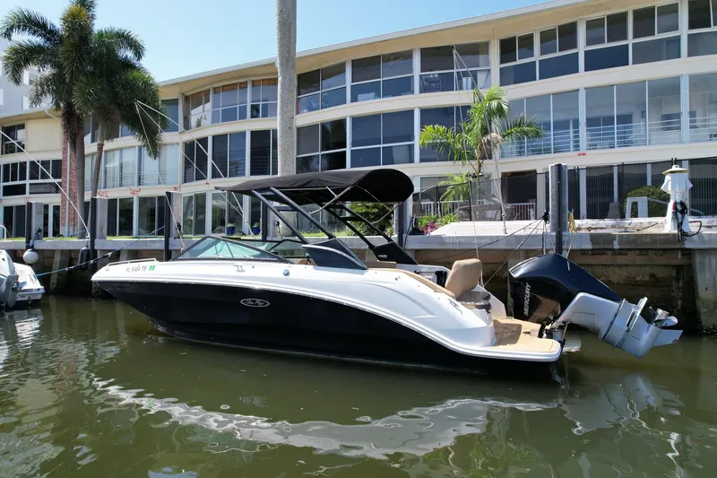 Slide: The Image of 2022 Sea Ray SLX 250 boat docked by waterfront apartments, featuring sleek design and modern amenities. - 2