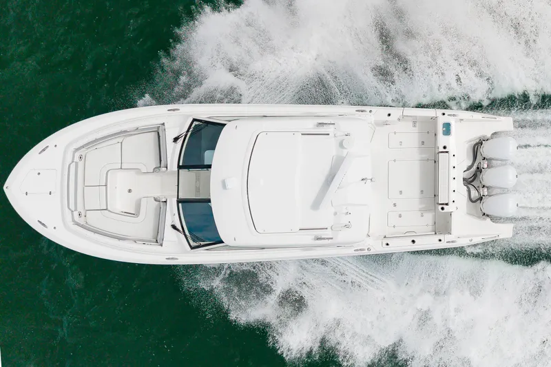 Slide: The Image of Aerial view of a white 2021 Pursuit DC 365 Dual Console boat speeding across the water. - 10