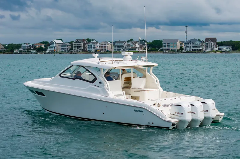 Slide: The Image of A white 2021 Pursuit DC 365 Dual Console boat on calm water. Coastal houses are visible in the background. - 9