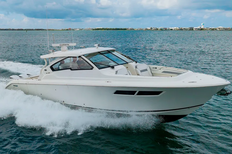 Slide: The Image of A 2021 Pursuit DC 365 Dual Console speeds across the water, surrounded by a coastal landscape. - 5