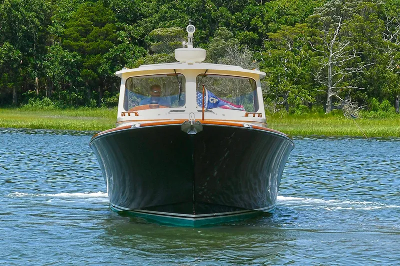Slide: The Image of 2015 Hinckley Talaria 34 cruising on a serene lake with lush green forest backdrop. - 28