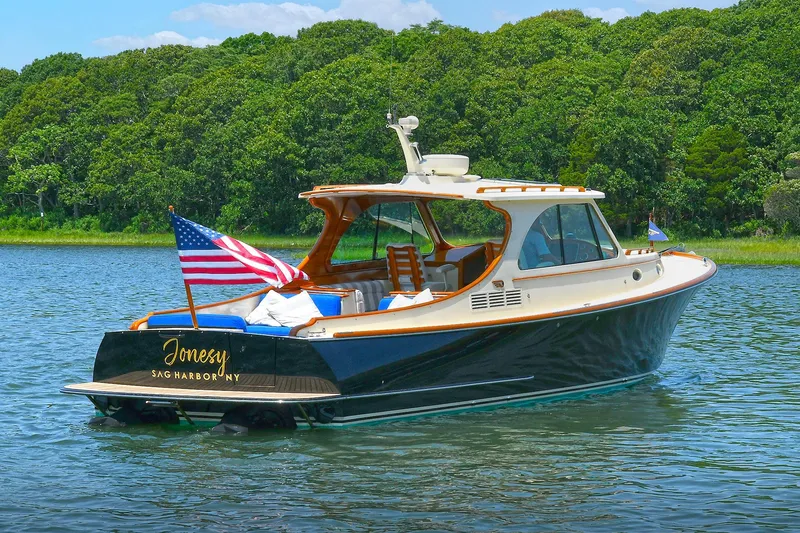 Slide: The Image of 2015 Hinckley Talaria 34 yacht on water, American flag, lush green background. - 32