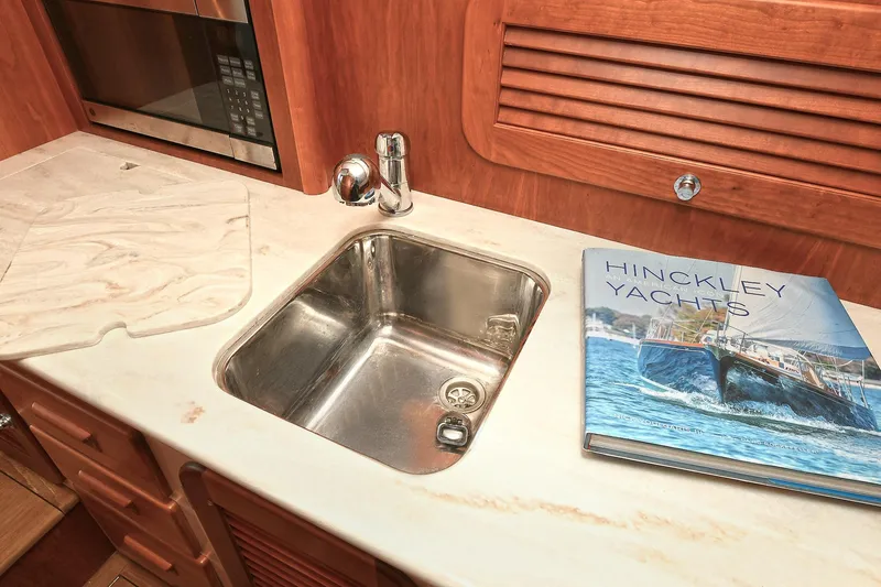 Slide: The Image of Hinckley Talaria 34 yacht kitchen with sink, countertop, and yacht book, 2015 model. - 20