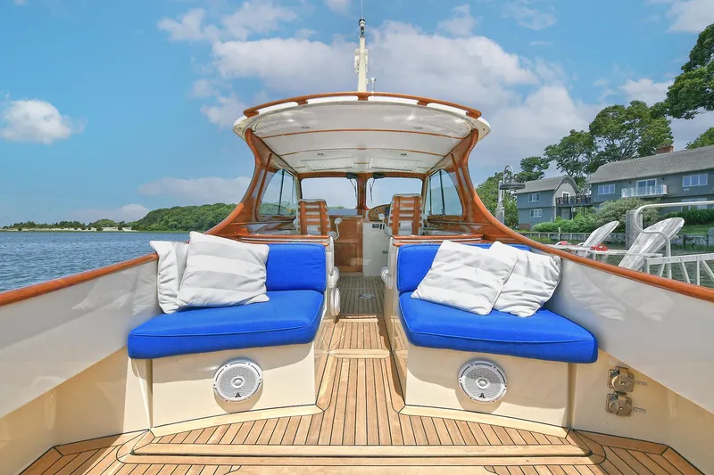 Slide: The Image of 2015 Hinckley Talaria 34 yacht with blue seating, docked by waterfront homes. - 15
