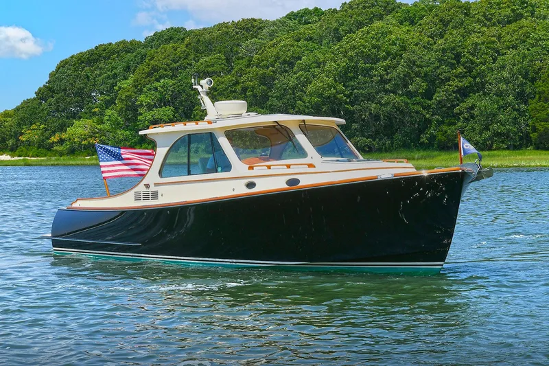 The Image of 2015 Hinckley Talaria 34 yacht cruising on a serene lake with lush green trees. - 0