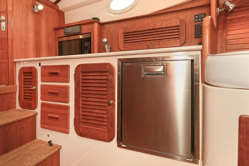 Slide: The Image of Hinckley Talaria 34 yacht interior, featuring wooden cabinetry and stainless steel appliances, 2015 model. - 21