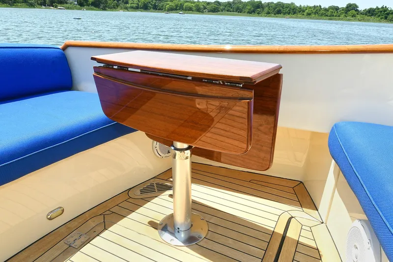 Slide: The Image of Luxury seating area on 2015 Hinckley Talaria 34 yacht with wooden table and blue cushions. - 17