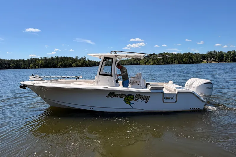 Slide: The Image of 2024 Sea Hunt Gamefish 27 Coffin Box boat on a serene lake under a clear blue sky. - 9