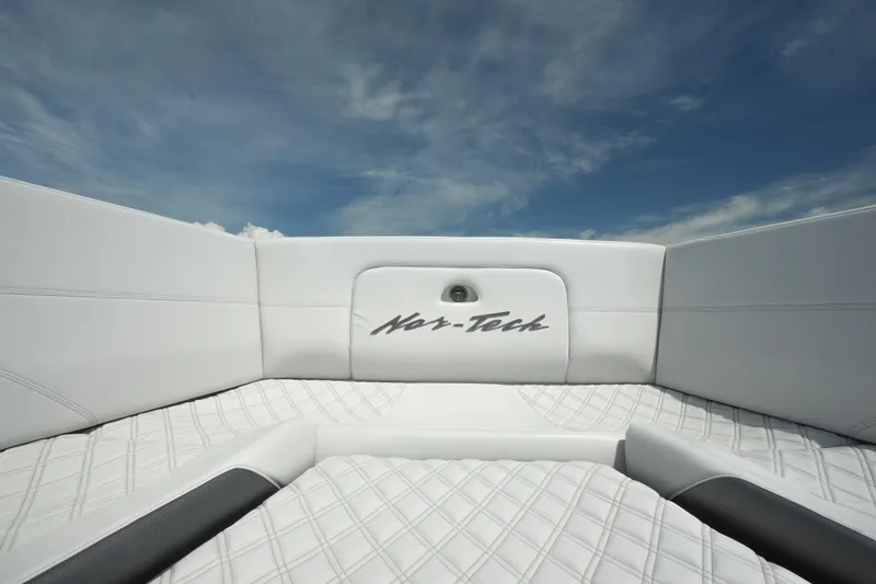 Slide: The Image of 2020 Nor-Tech 390 Sport Center Console boat interior with white quilted seating under blue sky. - 39