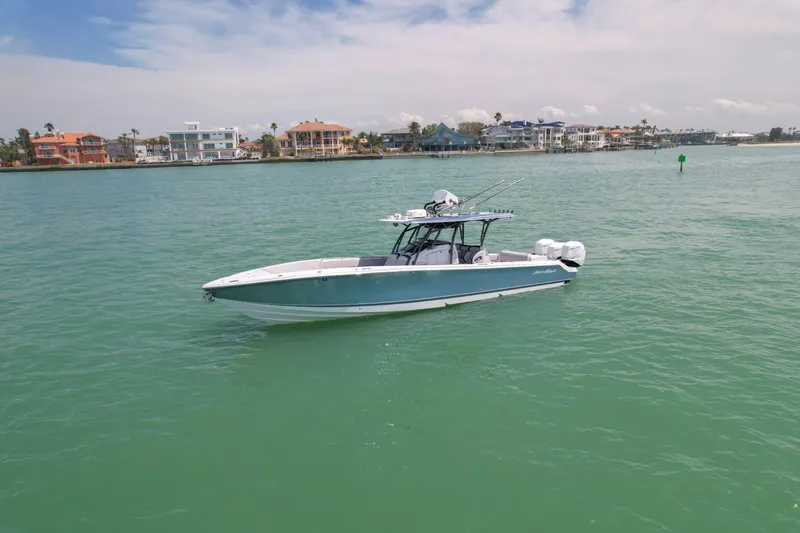 Slide: The Image of 2020 Nor-Tech 390 Sport Center Console boat on calm turquoise water near coastal homes. - 4