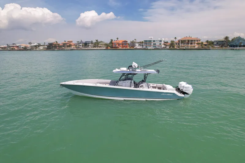 Slide: The Image of 2020 Nor-Tech 390 Sport Center Console boat on calm water, coastal homes in background. - 5