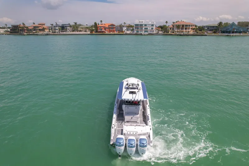 Slide: The Image of 2020 Nor-Tech 390 Sport Center Console cruising on calm waters near coastal homes. - 8